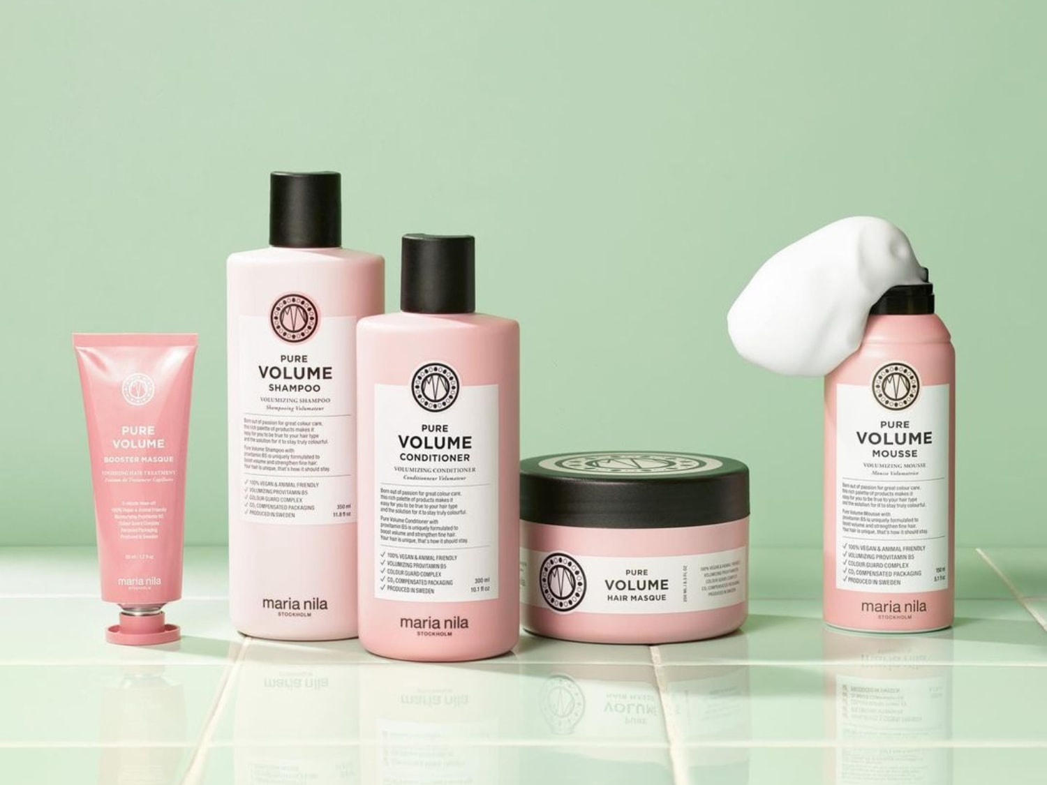 Eine Reihe von Maria Nila Pure Volume-Haarpflegeprodukten in rosa Verpackung, darunter Booster Masque, Shampoo, Conditioner, Haarmaske und Mousse.