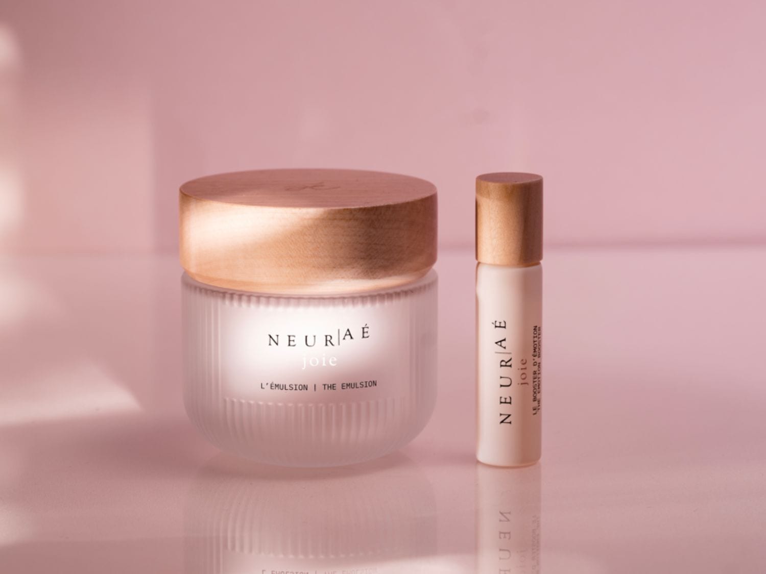 Découvrez NEUR/Aé joie L'ÉMULSION, un soin luxueux dans un pot en verre givré avec un couvercle en bois, et LE BOOSTER D'ÉMOTION dans un élégant flacon.