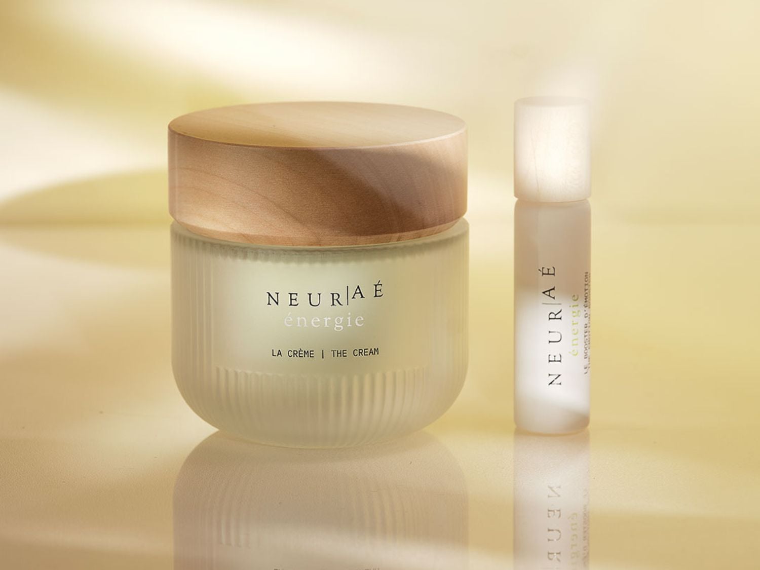 Découvrez NEUR/A Énergie La Crème, un soin revitalisant dans un pot givré avec un couvercle en bois, accompagné du Booster d'Émotion pour une peau éclatante.