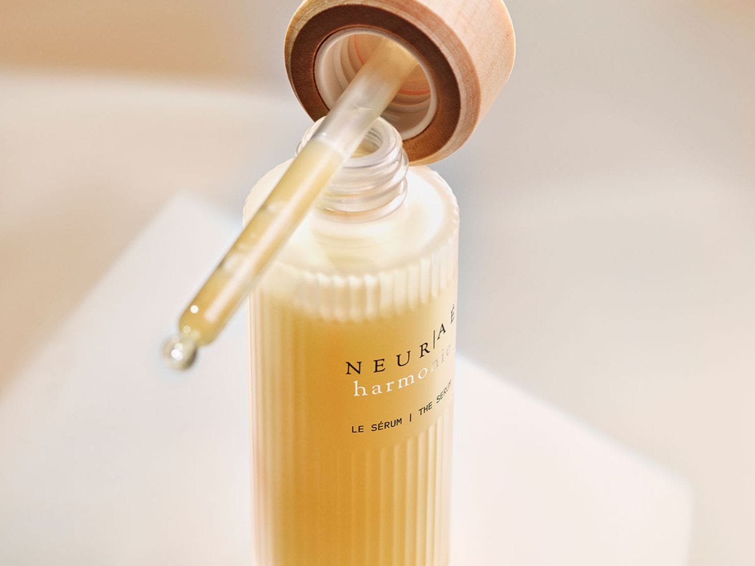 Découvrez le sérum NEUR/Aé harmonic dans son flacon élégant avec pipette, un soin précieux pour une peau éclatante.