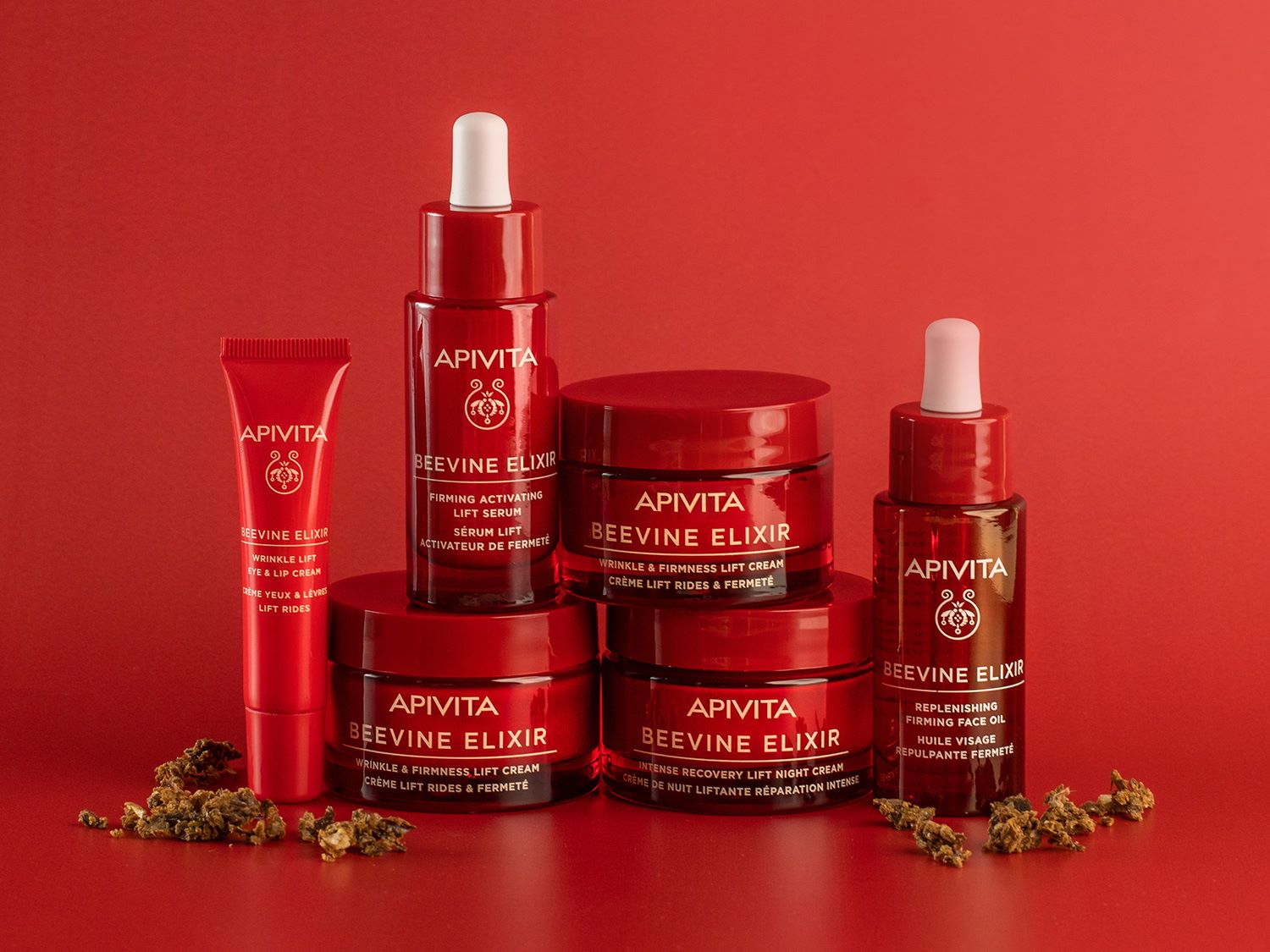 Descubre la colección Apivita Beevine Elixir, que incluye crema para ojos y labios, sérum, aceite facial y cremas de día y noche, todo en envases rojos.