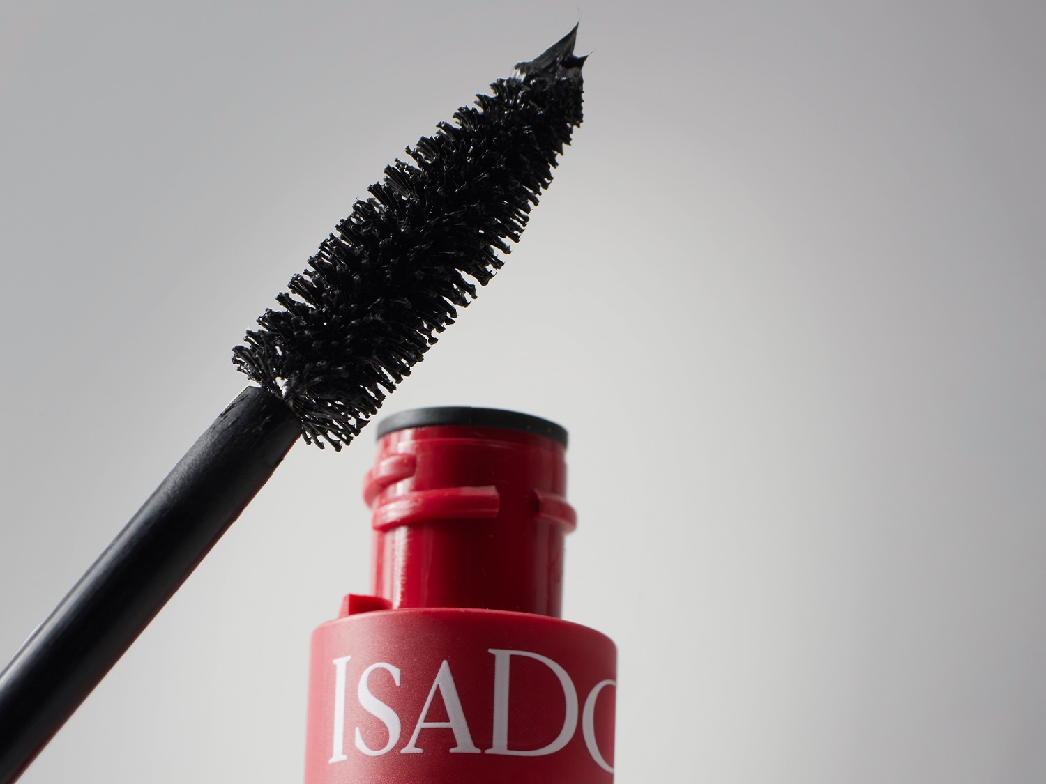 Nahaufnahme einer ISADORA-Mascara mit einer schwarzen Bürste und einer roten Verpackung, die eine vollständige und dichte Abdeckung für einen dramatischen Augenaufschlag verspricht.