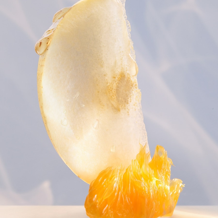 Nahaufnahme einer Birnenscheibe, die auf einer Mandarine balanciert und Frische und natürliche Schönheit ausstrahlt.