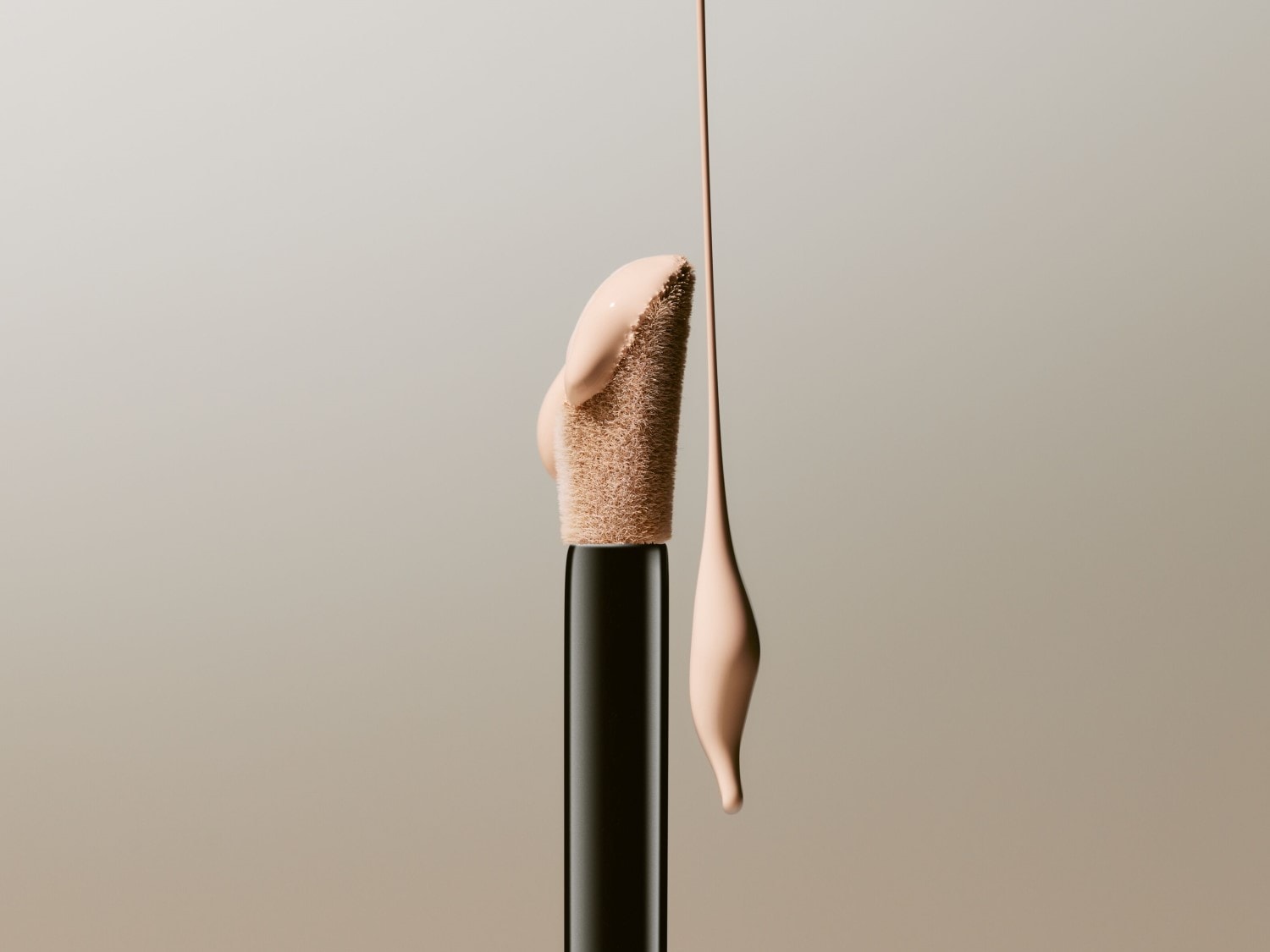 Nahaufnahme eines Make-up-Applikators mit einem Tropfen beiger Flüssigkeit, der von der Spitze tropft, vor einem neutralen Hintergrund.