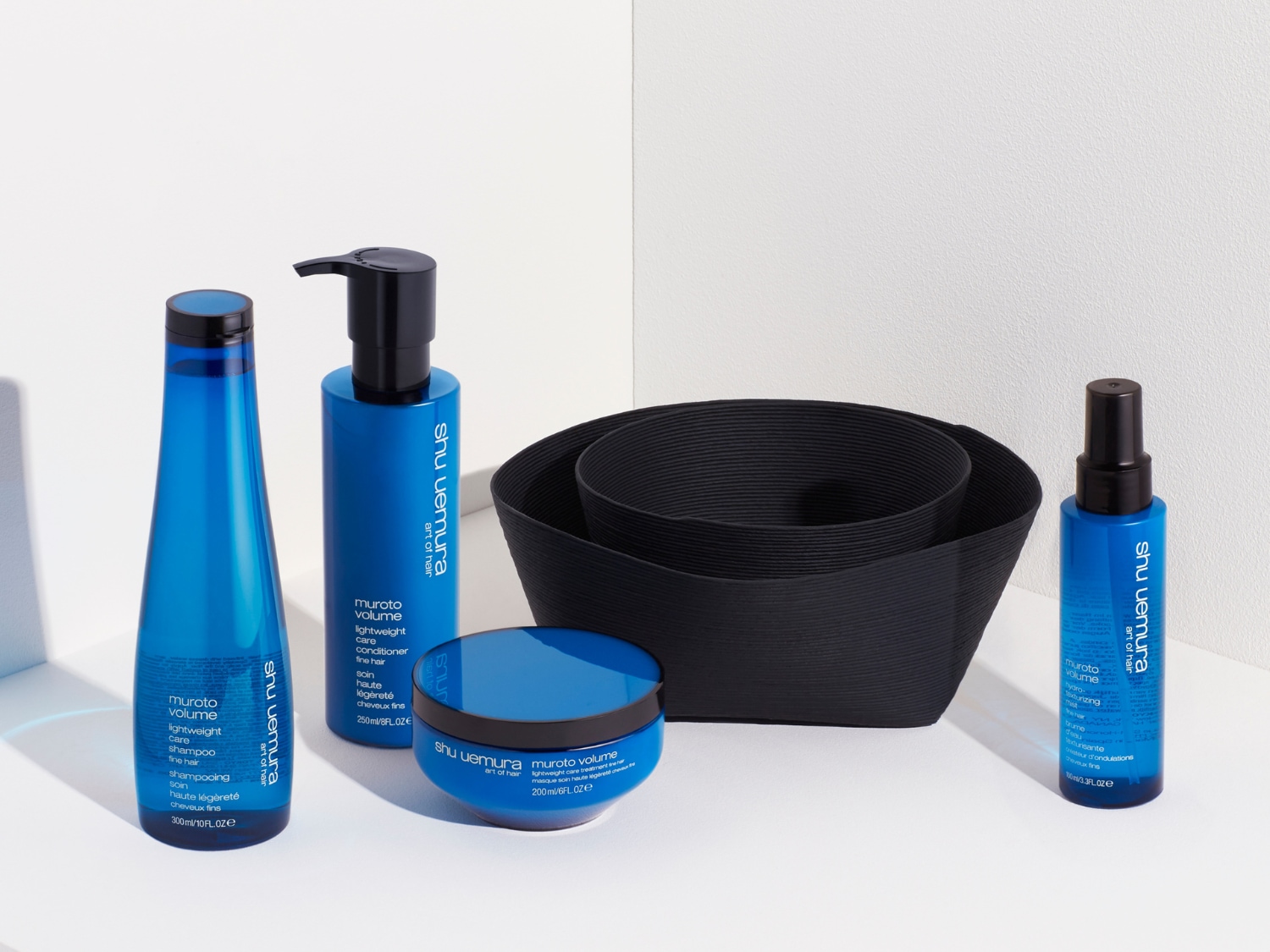 Súprava vlasovej kozmetiky Shu Uemura Muroto Volume v modrom balení obsahuje šampón, kondicionér, masku a sprej pre jemné vlasy.