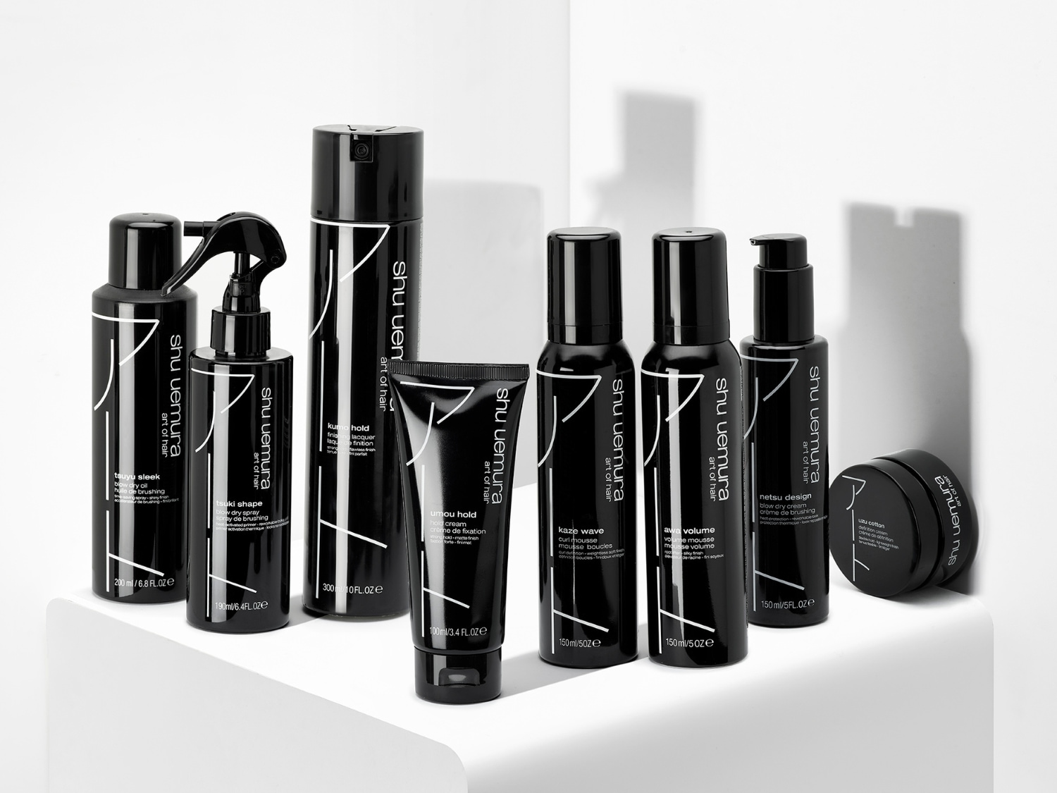 Čierne balenia vlasovej kozmetiky Shu Uemura Art of Hair, vrátane sprejov, olejov a krémov na úpravu vlasov.