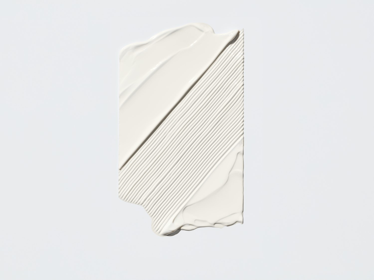 Nahaufnahme eines weißen Cremeprodukts mit glatter Textur, das in diagonalen Linien aufgetragen wurde und eine gleichmäßige, deckende Schicht bildet.