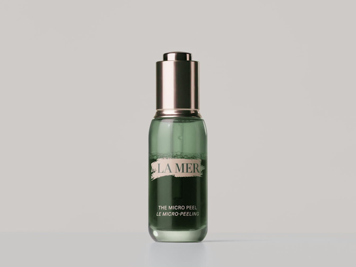 Groene glazen fles La Mer The Micro Peel met gouden dop, die een zachte maar effectieve peeling belooft voor een stralende huid.