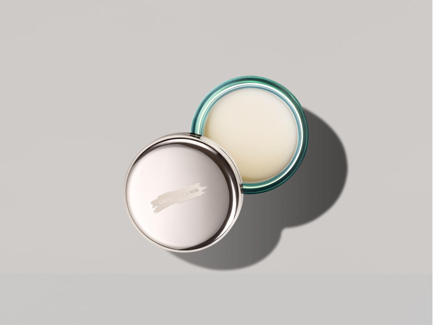 De Crème de la Mer is een zachte, witte crème in een zilveren pot met een groene rand.