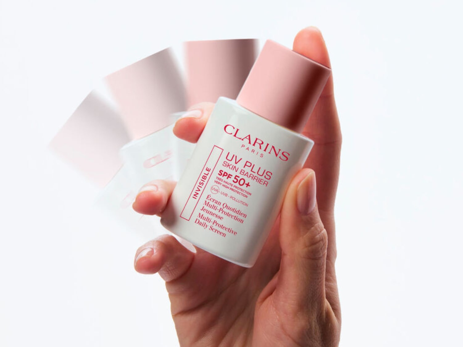 Una mano sostiene el protector solar Clarins UV Plus Skin Barrier SPF 50+, un protector diario multiprotector con muy alta protección contra los rayos UVA, UVB y la contaminación.