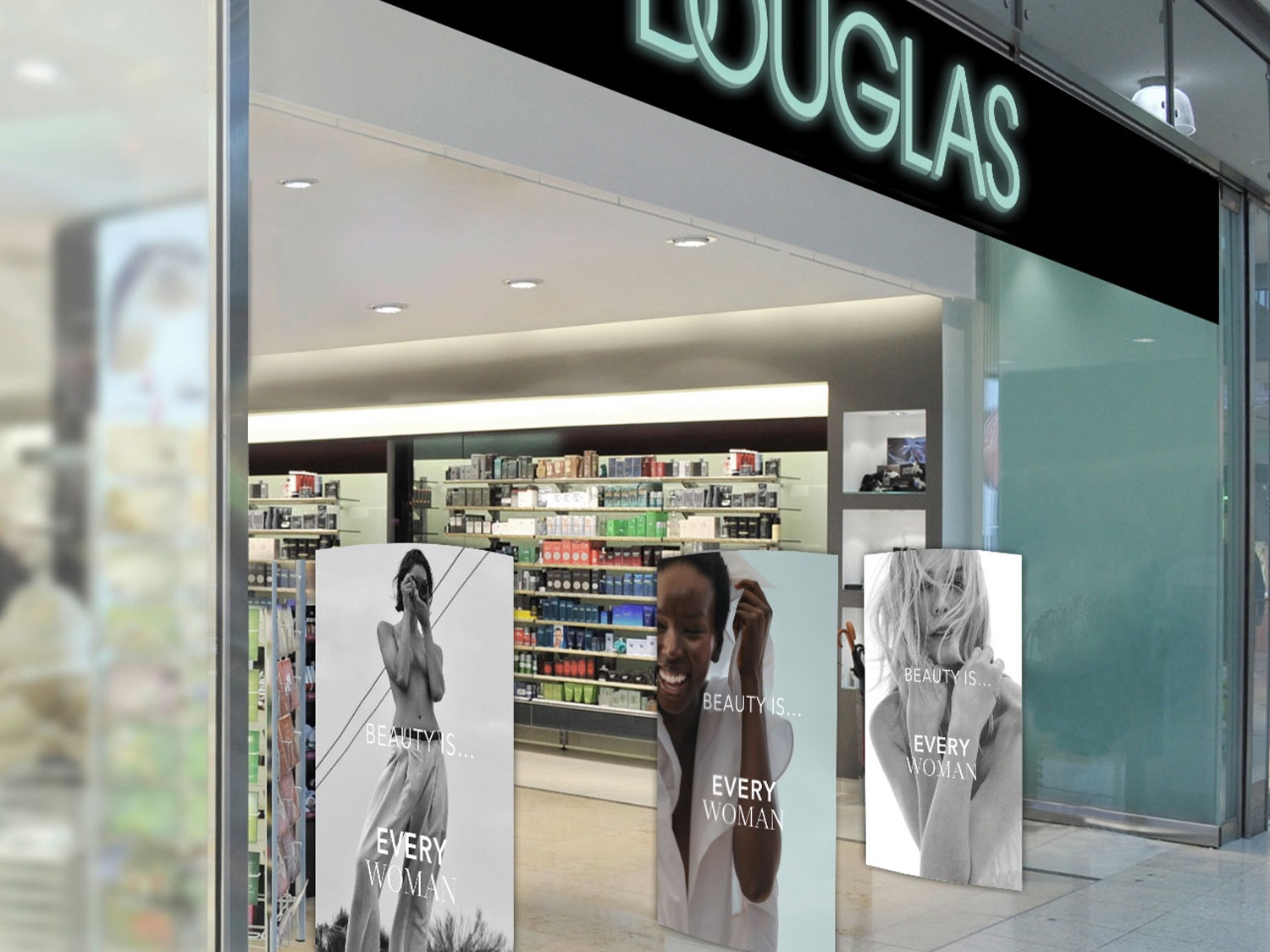 La entrada de Douglas presenta una fachada iluminada con el letrero de la marca y tres carteles que muestran a mujeres en blanco y negro con el texto "La belleza es... cada mujer".