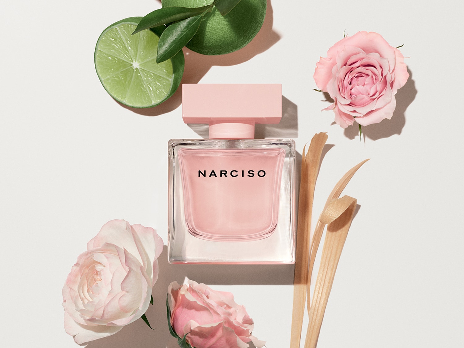 Découvrez Narciso, un parfum floral et fruité dans un flacon carré transparent avec un bouchon rose, entouré de roses et de limes fraîches.