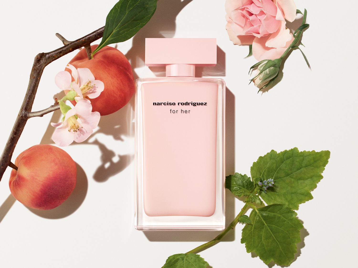 Découvrez le parfum Narciso Rodriguez For Her, un floral délicat dans un flacon rose poudré, entouré de pêches fraîches et de roses épanouies.