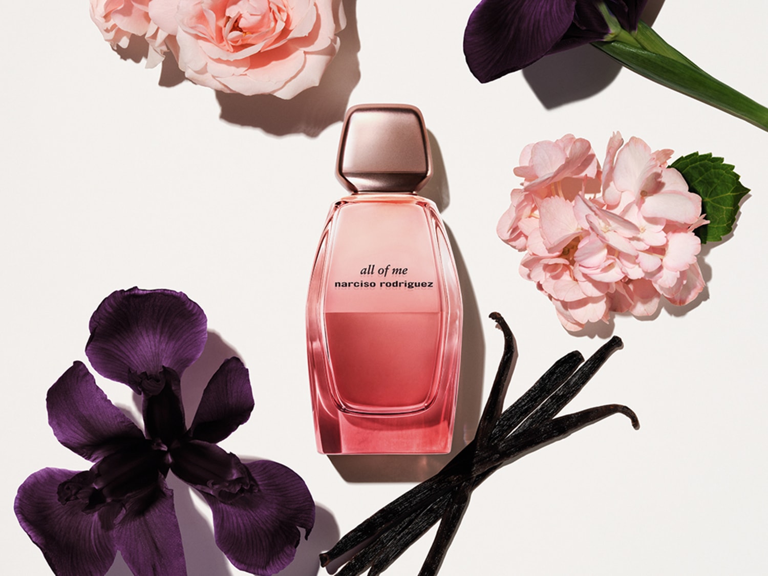Découvrez le parfum « all of me » de narciso rodriguez, un mélange floral et musqué dans un flacon dégradé rose, entouré de roses et d'iris.