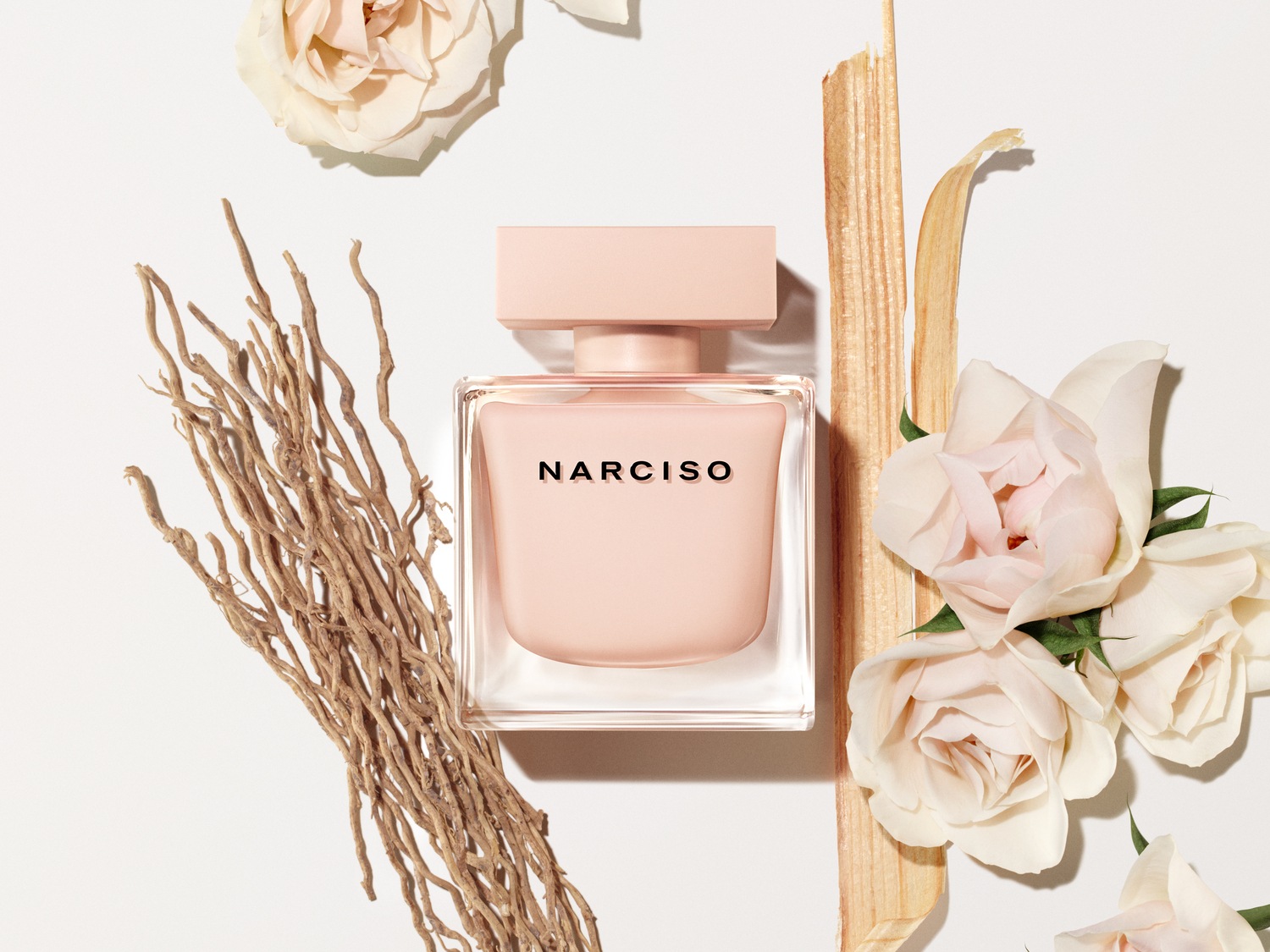 Découvrez Narciso, un parfum floral et poudré dans un flacon rose délicat, entouré de roses pâles et de touches naturelles pour une élégance subtile.
