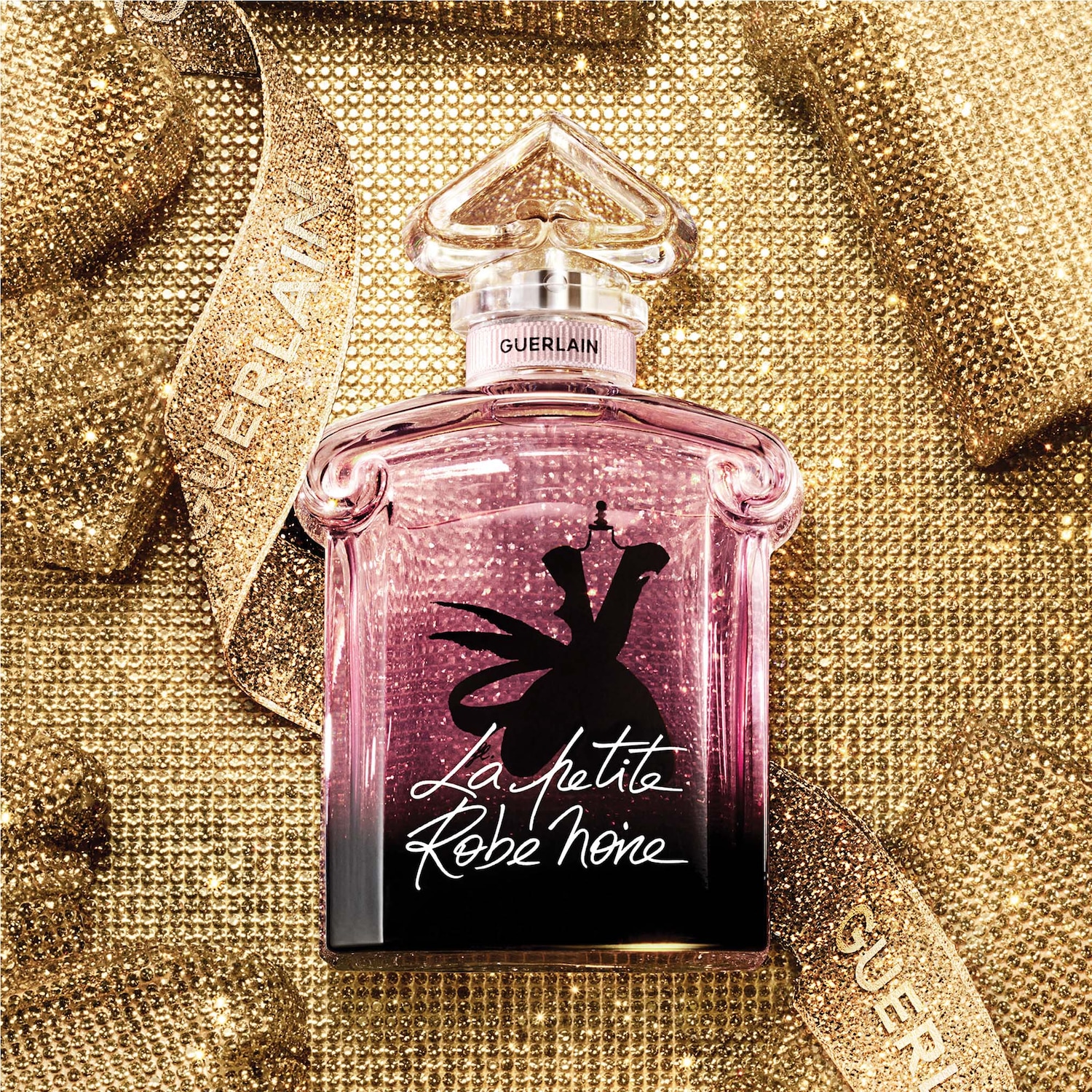 Découvrez La Petite Robe Noire de Guerlain, un parfum élégant dans un flacon rose orné d'une robe noire, sur un fond doré scintillant.