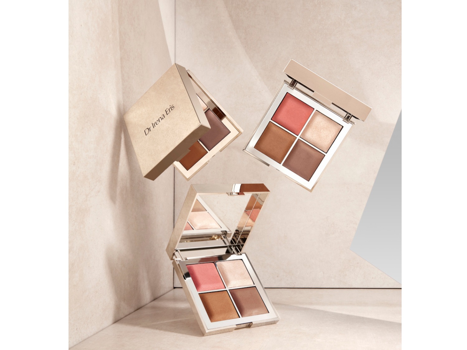 Trzy palety do makijażu Dr Irena Eris unoszą się w powietrzu, każda zawiera cztery odcienie: różu, brązu i rozświetlacza, idealne do konturowania i podkreślania rysów twarzy.