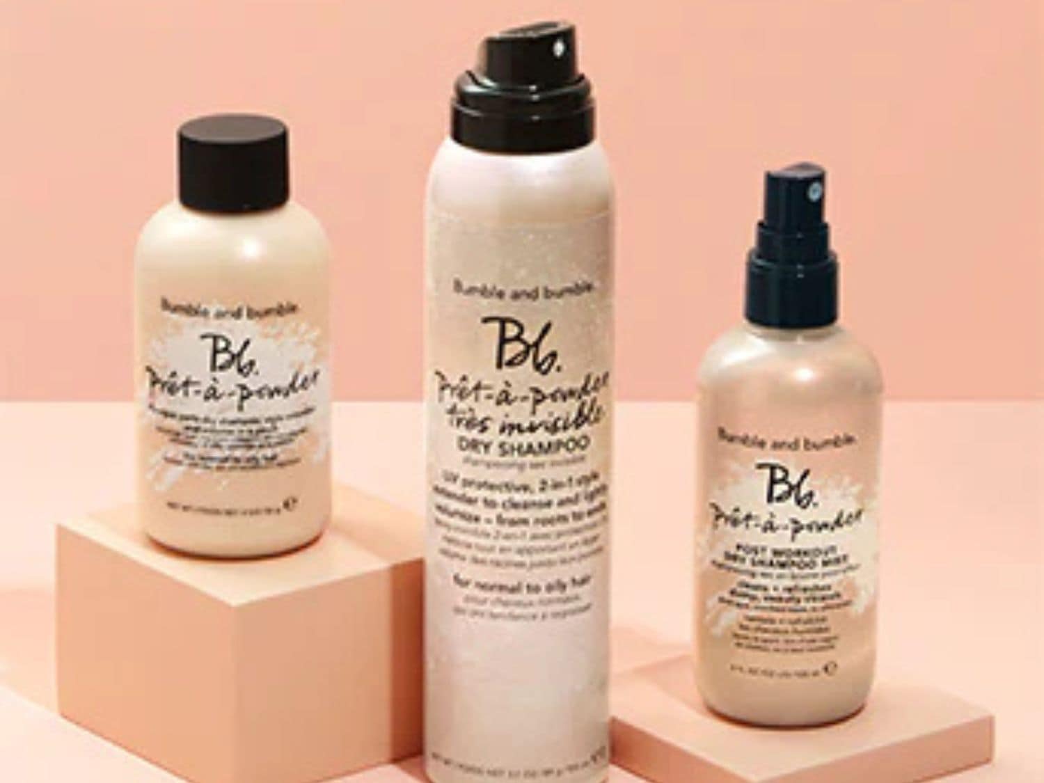 Tři lahve suchého šamponu Bumble and Bumble Prêt-à-powder v béžových obalech s černými víčky, které slibují osvěžení a oživení vlasů.