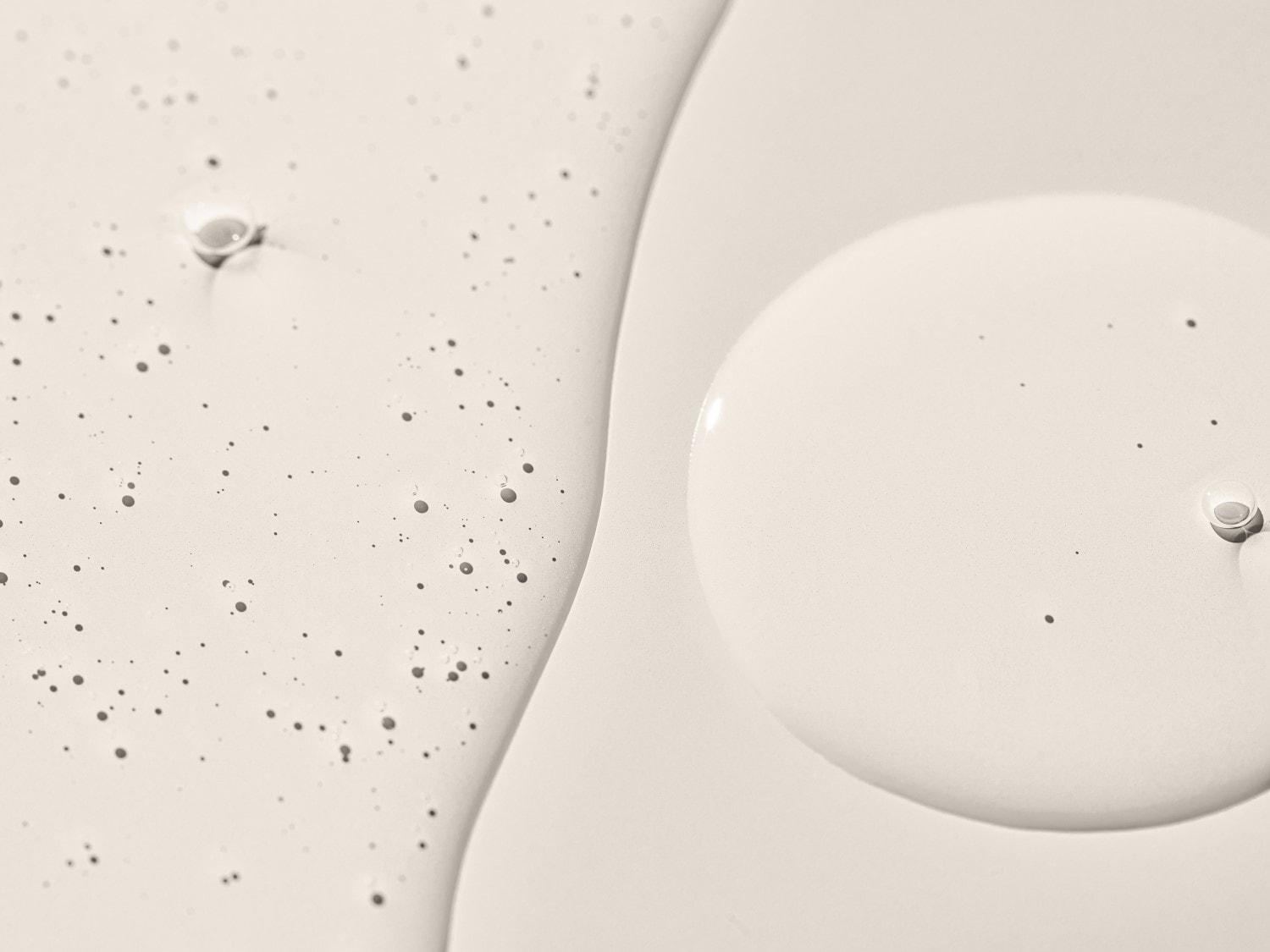Nahaufnahme einer beigen Flüssigkeit mit kleinen Bläschen und einer glatten, kreisförmigen Oberfläche, die eine feuchtigkeitsspendende oder reinigende Textur für die Hautpflegeprodukte zeigt.