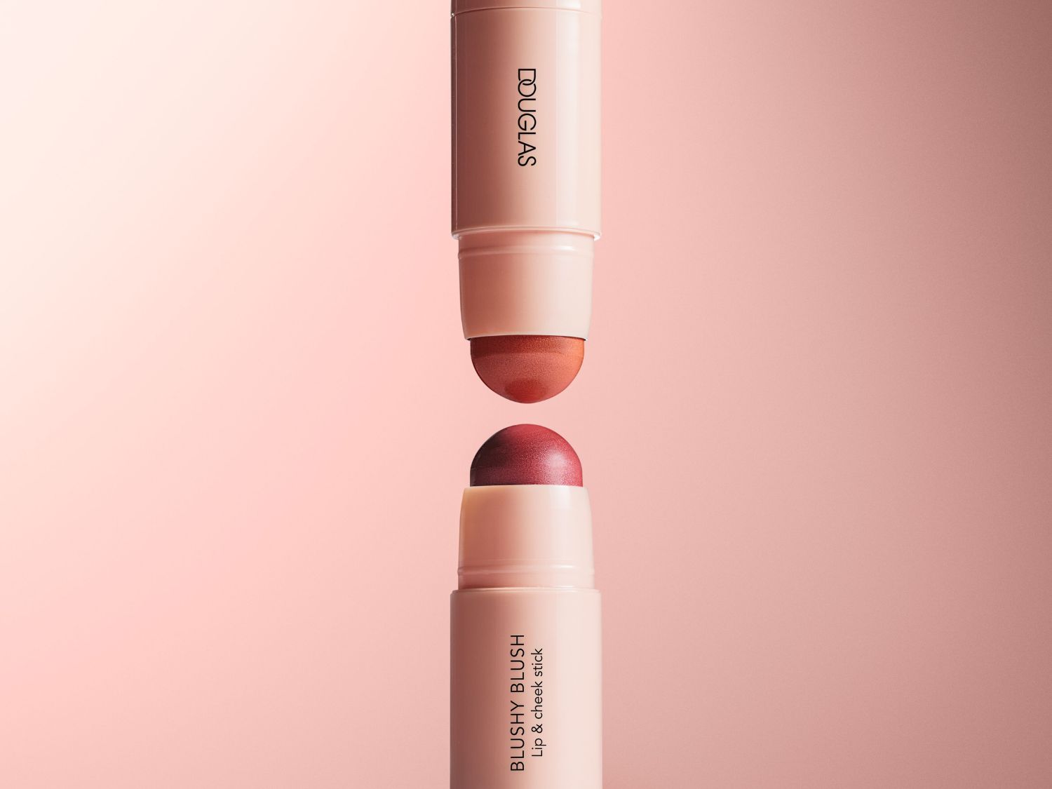 Dwa sztyfty do ust i policzków Douglas Blushy Blush w odcieniach różu i czerwieni, idealne do makijażu.