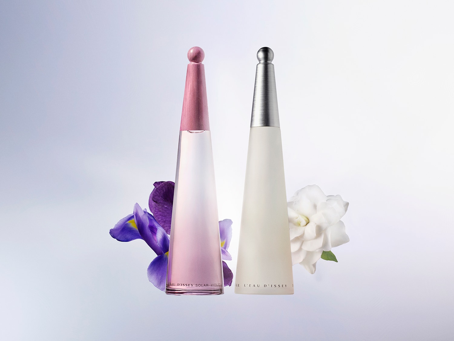 Dwa flakony perfum Issey Miyake w kształcie stożków, jeden różowy z fioletowymi kwiatami, drugi biały z białymi kwiatami, na jasnym tle.