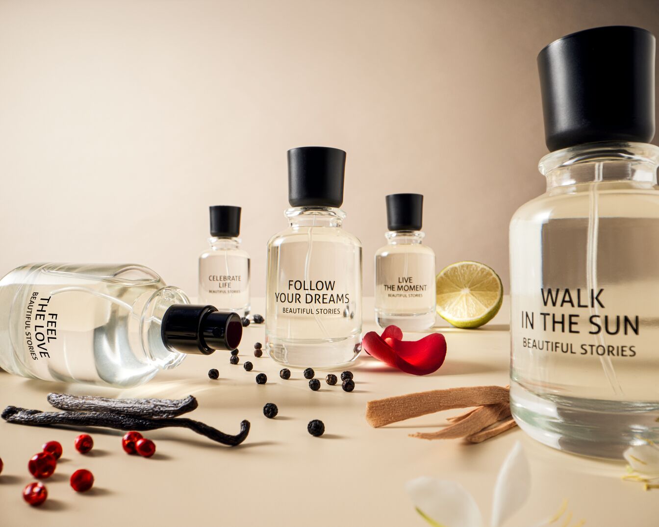 Eine Sammlung von Parfümflaschen mit Aufschriften wie "Feel the Love", "Celebrate Life", "Follow Your Dreams", "Live the Moment" und "Walk in the Sun", umgeben von Vanille, roten Beeren und Limetten.