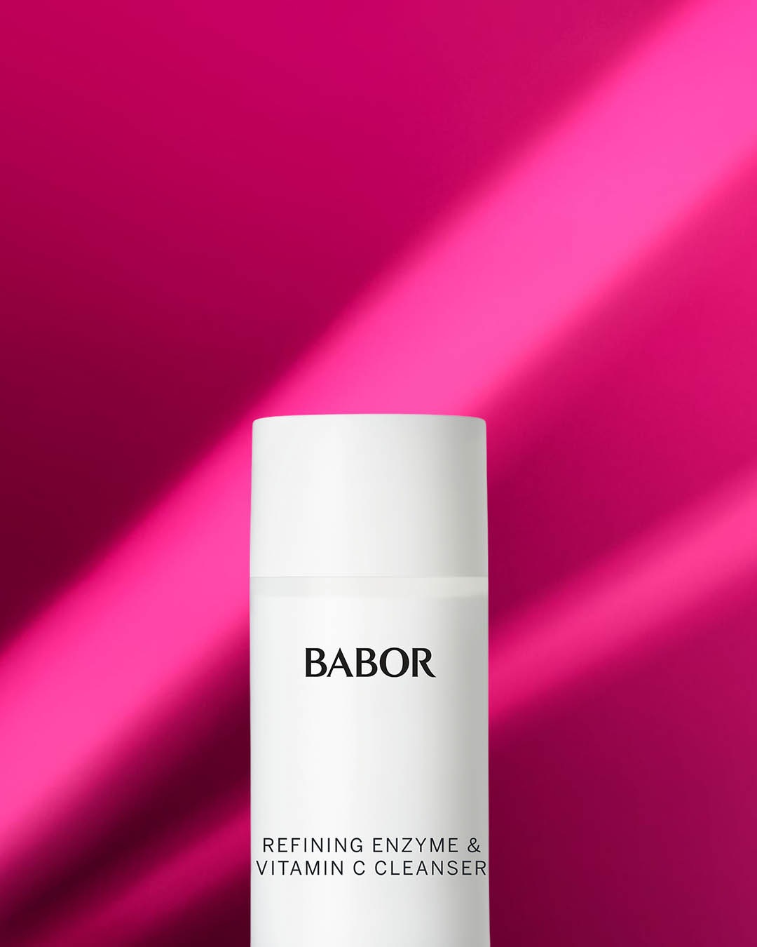 Biała butelka BABOR Refining Enzyme & Vitamin C Cleanser na tle różowego światła, idealna do oczyszczania i odświeżania skóry.