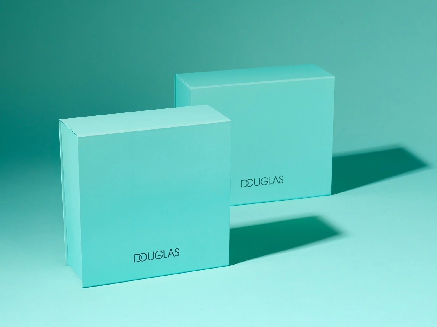 Du žalios spalvos „Douglas“ prekės ženklo kosmetikos rinkiniai, skirti dovanoms įteikti.