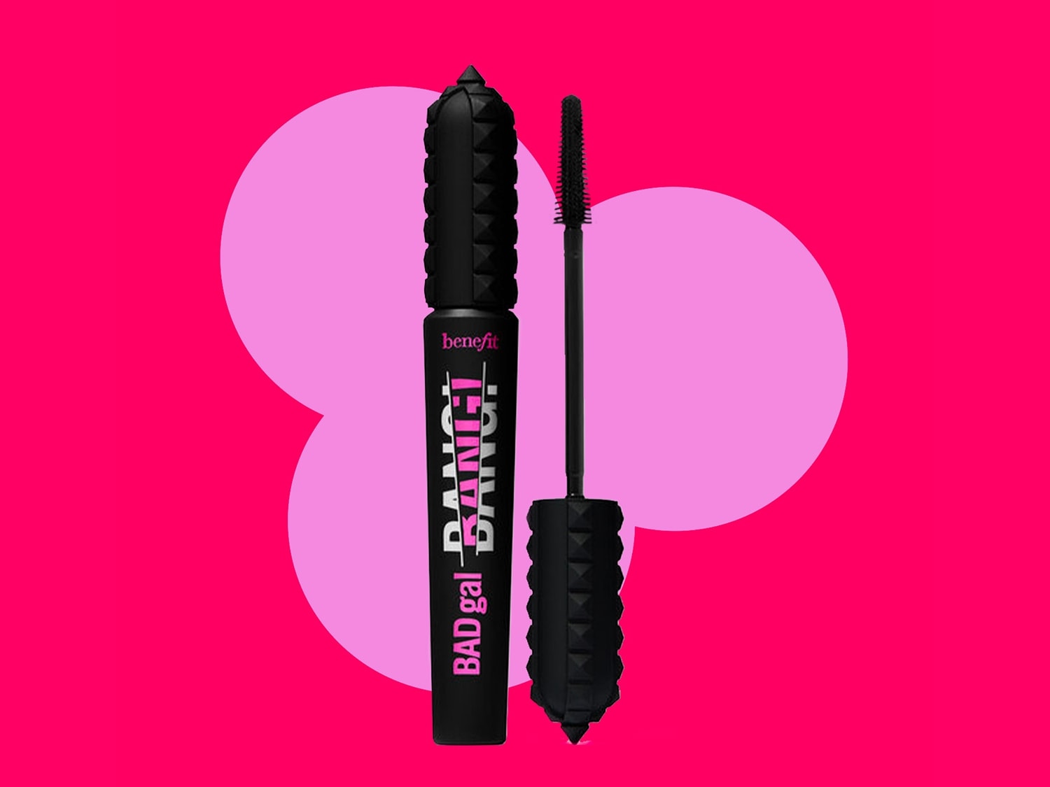 Benefit BADgal BANG! Mascara in schwarzer, nietenbesetzter Verpackung mit pinkfarbenem Schriftzug, daneben eine Bürste vor pinkfarbenem Hintergrund.