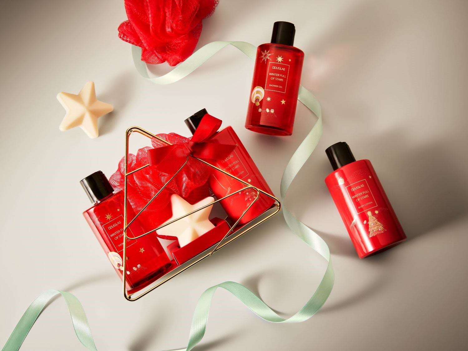 Darčeková súprava Douglas Winter Full of Stars s červenými fľaštičkami sprchového gélu a telového mlieka, ozdobená červenou stuhou a hviezdou.