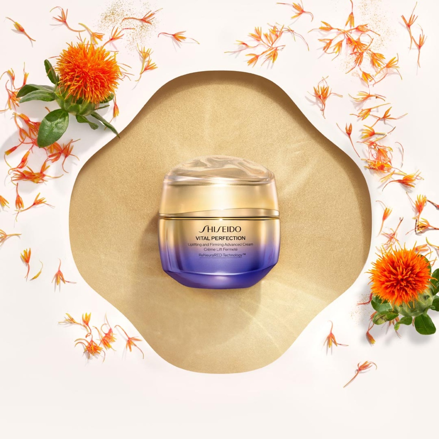 De Shiseido Vital Perfection crème in een goudkleurige en paarse verpakking, omringd door oranje bloemblaadjes, belooft een liftend effect.