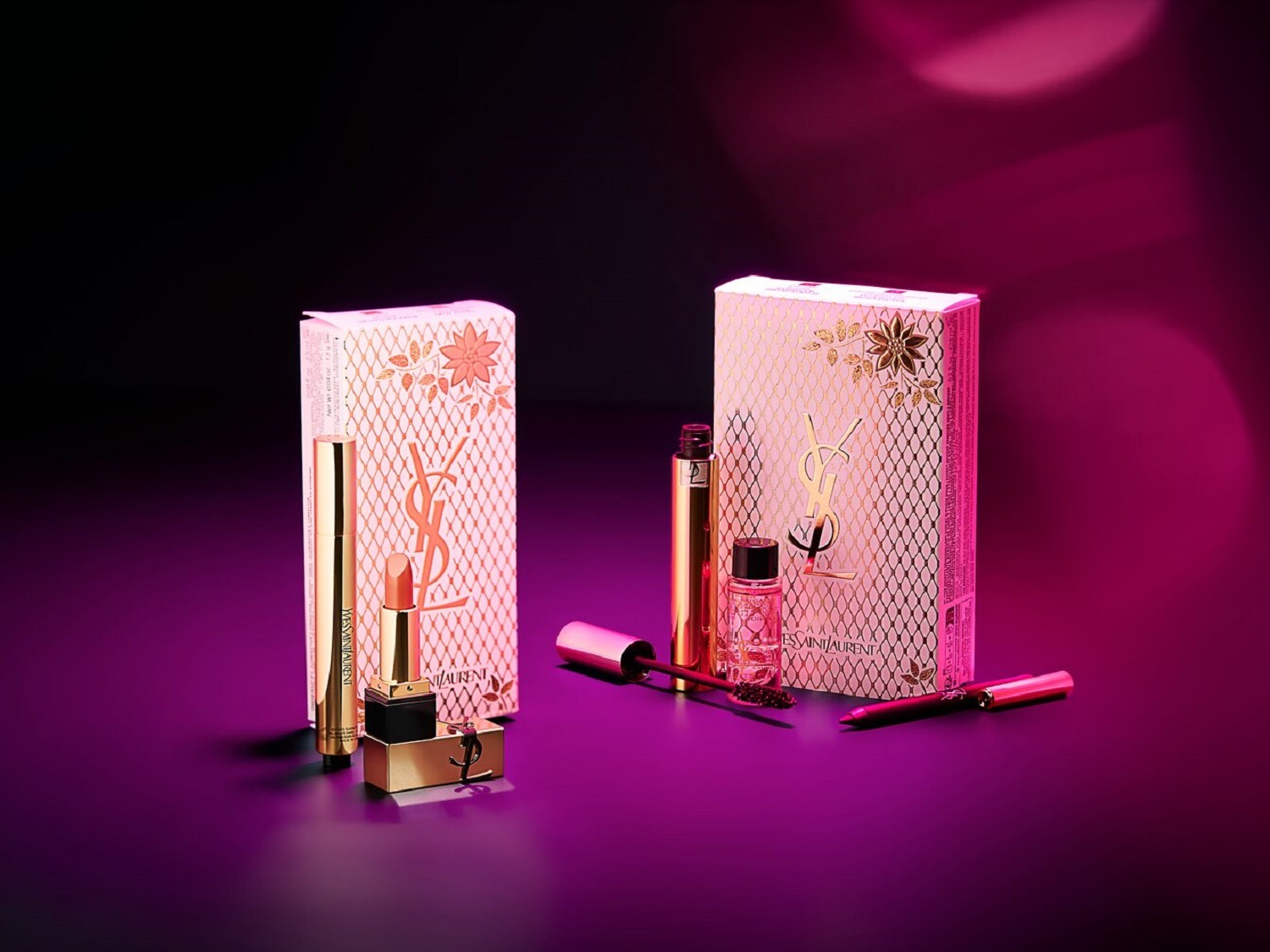 Zestaw upominkowy Yves Saint Laurent z pudrowo-różowym opakowaniem ozdobionym złotymi detalami, zawierający szminkę, tusz do rzęs i perfumy, idealny na prezent.