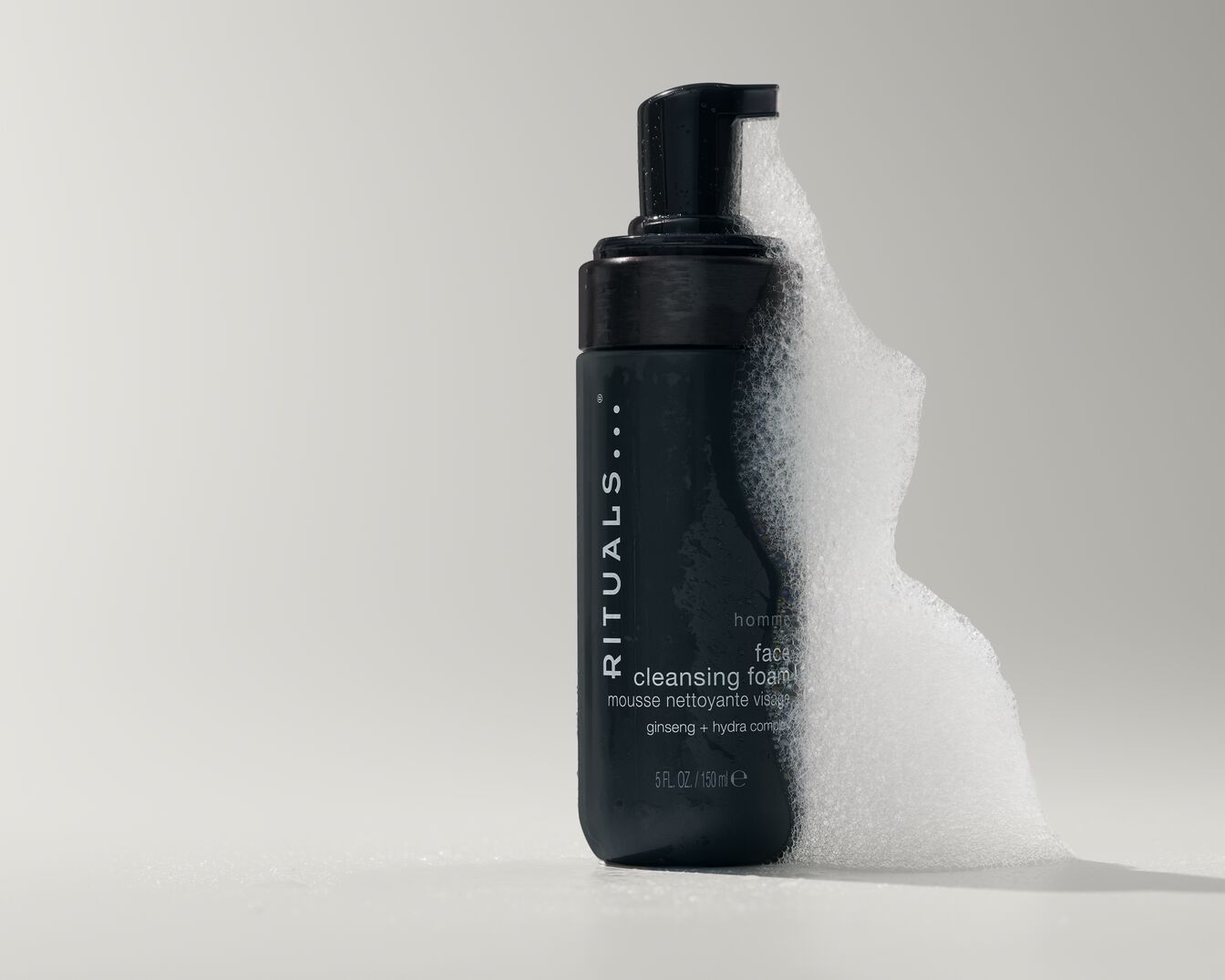 Die schwarze Flasche Rituals Homme Gesichtsschaum mit Ginseng und Hydra-Komplex ist mit einer Pumpe versehen, aus der weißer Schaum austritt.