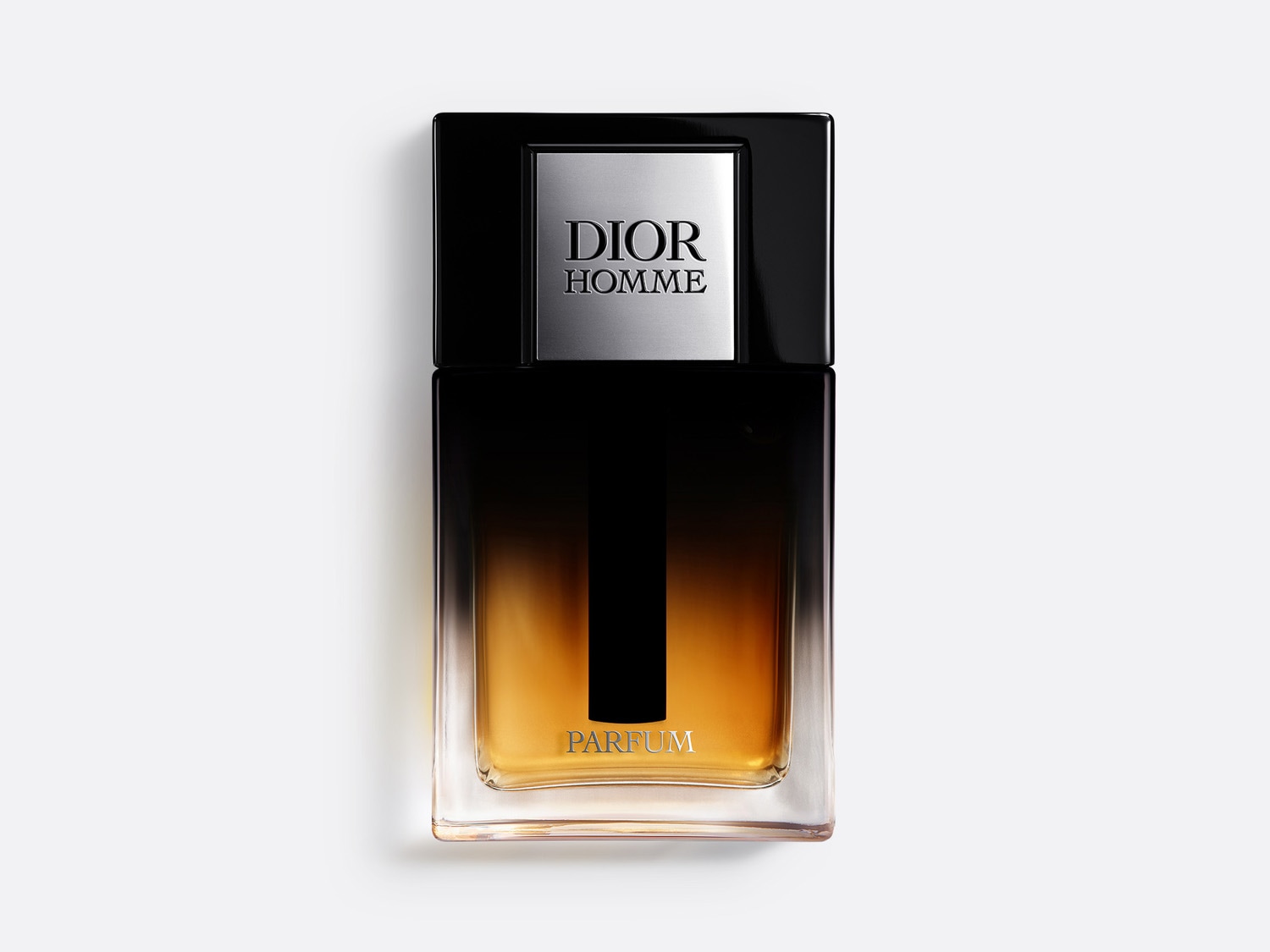 El frasco de perfume Dior Homme tiene una tapa negra brillante con una placa plateada grabada con 'DIOR HOMME', mientras que la parte inferior del frasco revela un líquido ámbar que indica 'PARFUM'.