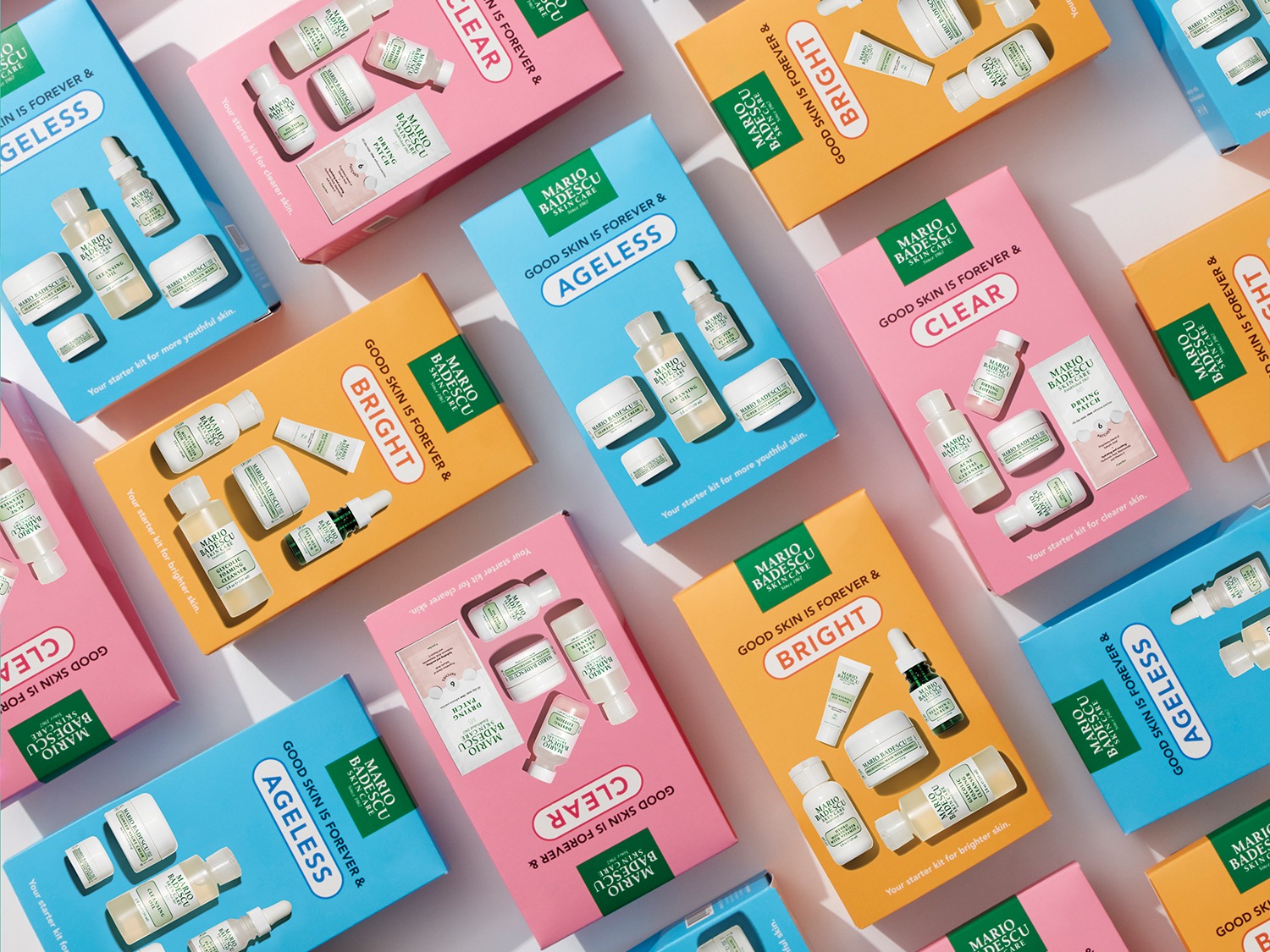 Een assortiment Mario Badescu huidverzorgingssets in blauwe, gele en roze verpakkingen, elk met de tekst 'Good skin is forever' en gericht op heldere, jeugdige en stralende huid.