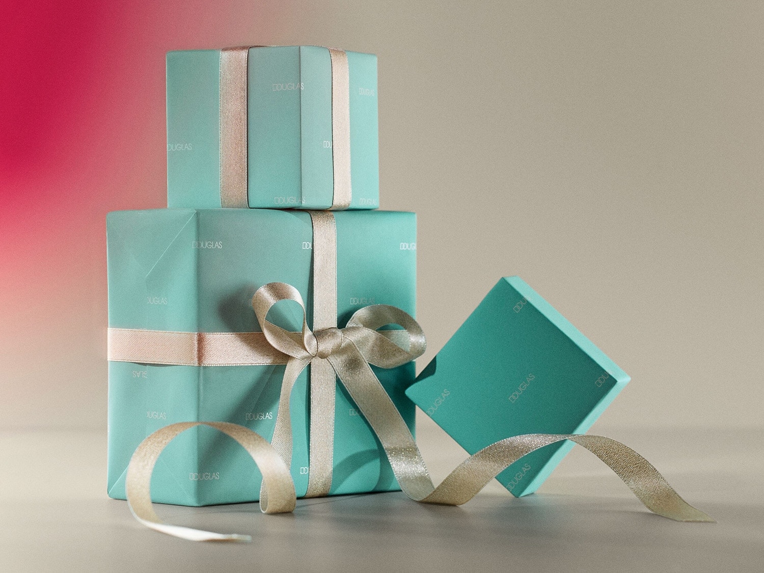 Aquí hay una pila de regalos envueltos en papel azul verdoso con el logo de Douglas, atados con una cinta dorada brillante, listos para cualquier celebración.