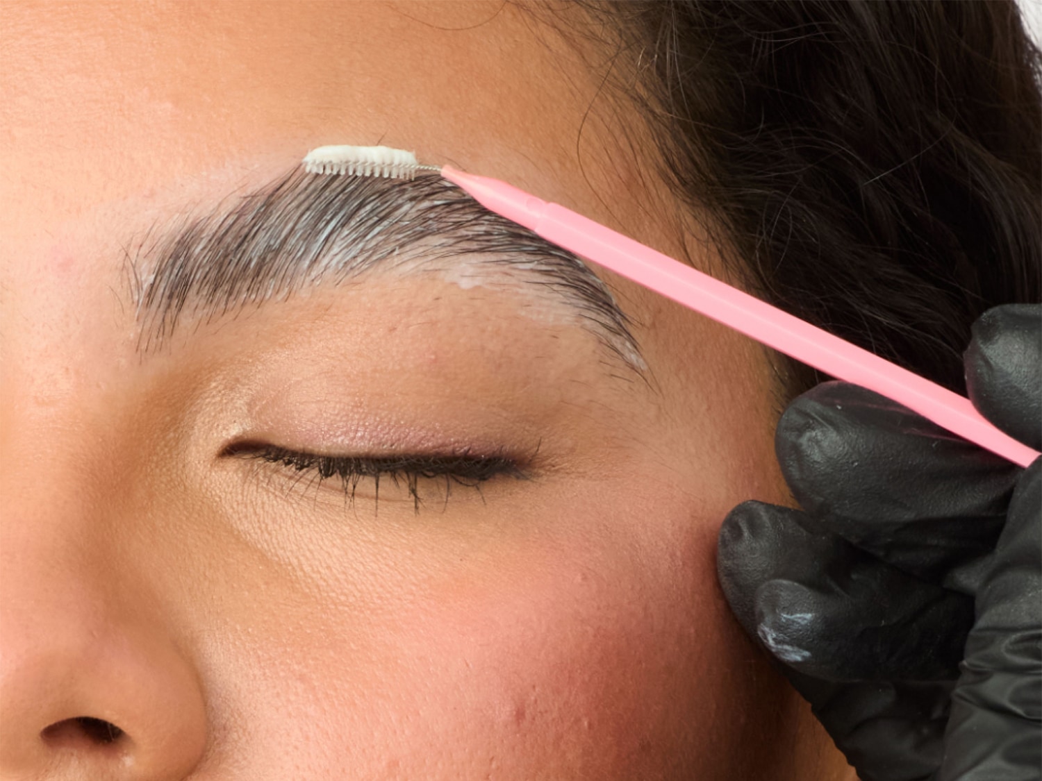 Nahaufnahme einer Person, die sich mit einem Pinsel und einem weißen Produkt die Augenbrauen macht, um einen präzisen und gepflegten Look zu erzielen.