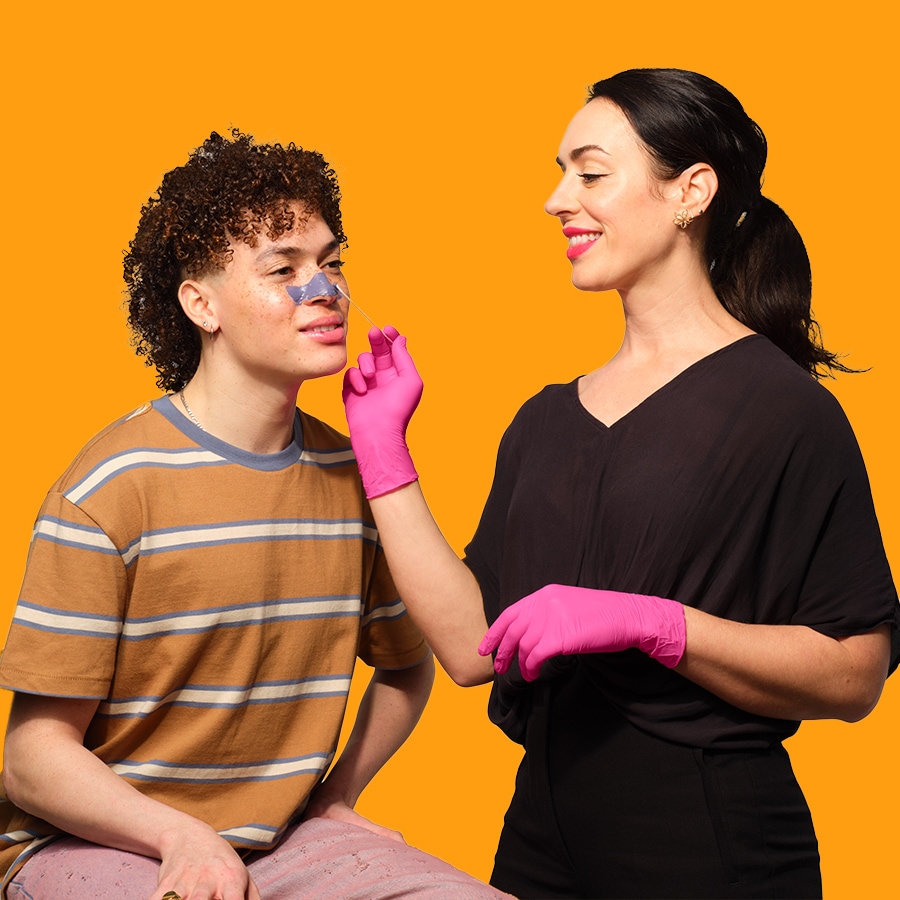 Eine Kosmetikerin mit pinkfarbenen Handschuhen trägt einem jungen Mann einen Nasenstreifen auf, um seine Hautpflegeroutine zu verbessern.
