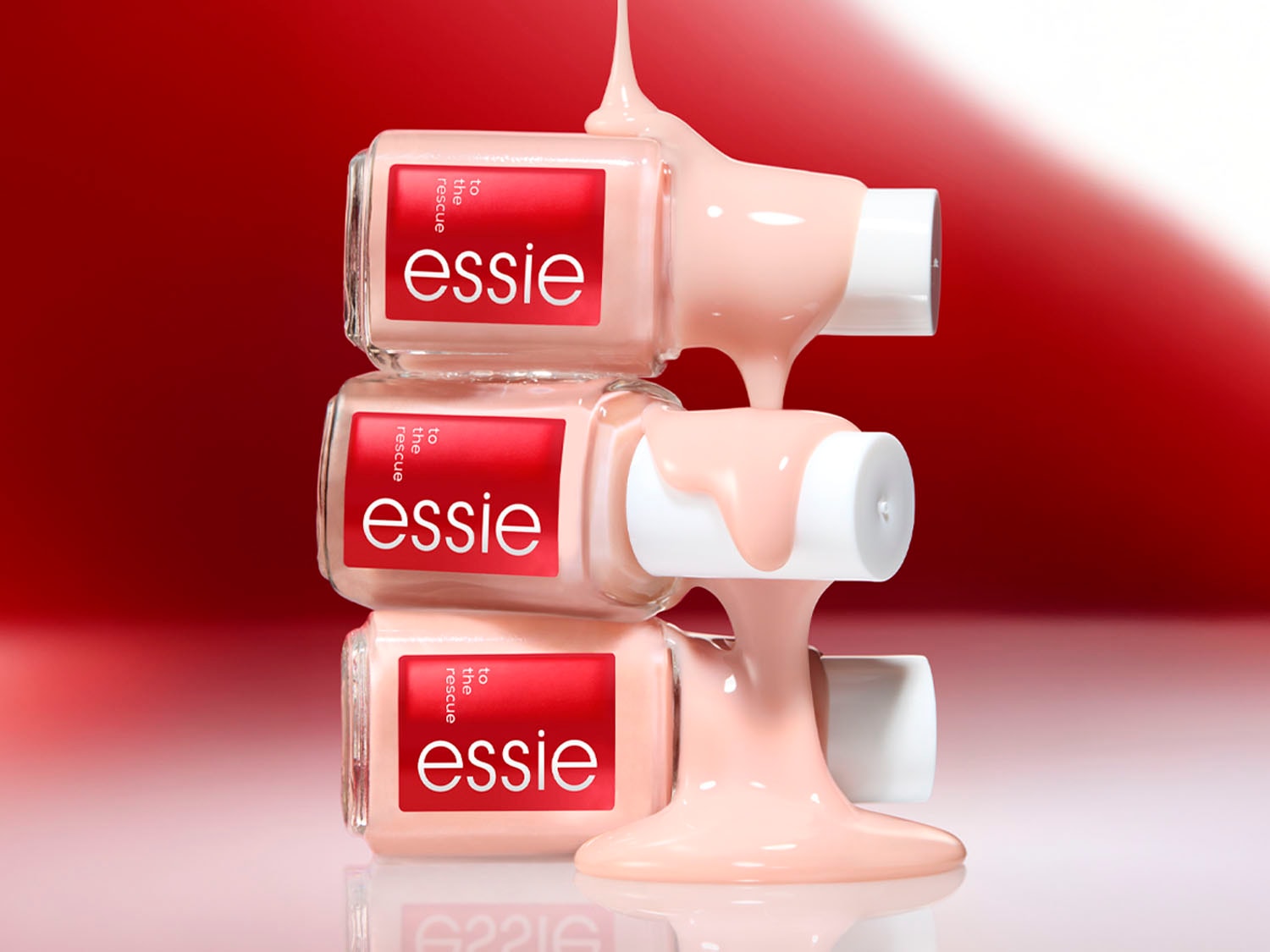 Tres frascos de esmalte Essie apilados uno encima del otro, con esmalte color melocotón derramándose, sobre un fondo rojo.
