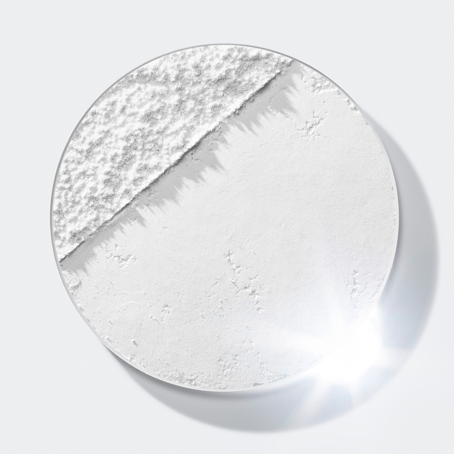 Nahaufnahme eines runden Behälters, der teilweise mit einem körnigen, puderartigen Material und einem glatten, weißen Puder gefüllt ist.