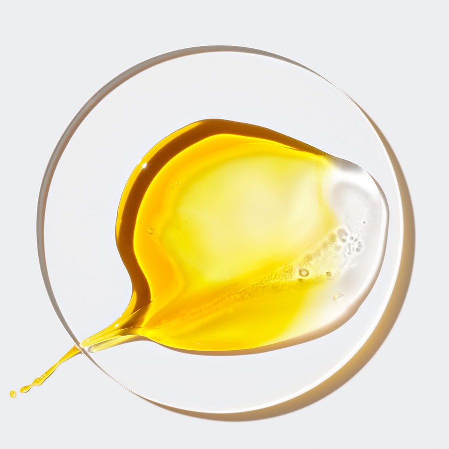 Nahaufnahme einer gelben Flüssigkeit, die auf einer transparenten Oberfläche verschmiert ist und eine klare, glänzende Textur aufweist.