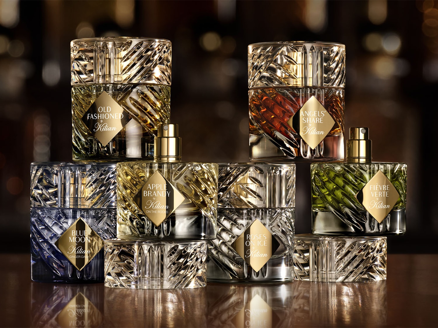 Kilian parfümök gyűjteménye, köztük az Old Fashioned, Angels' Share, Blue Moon, Apple Brandy, Roses on Ice és Fièvre Verte, mindegyik egyedi, texturált üvegben és arany címkével.