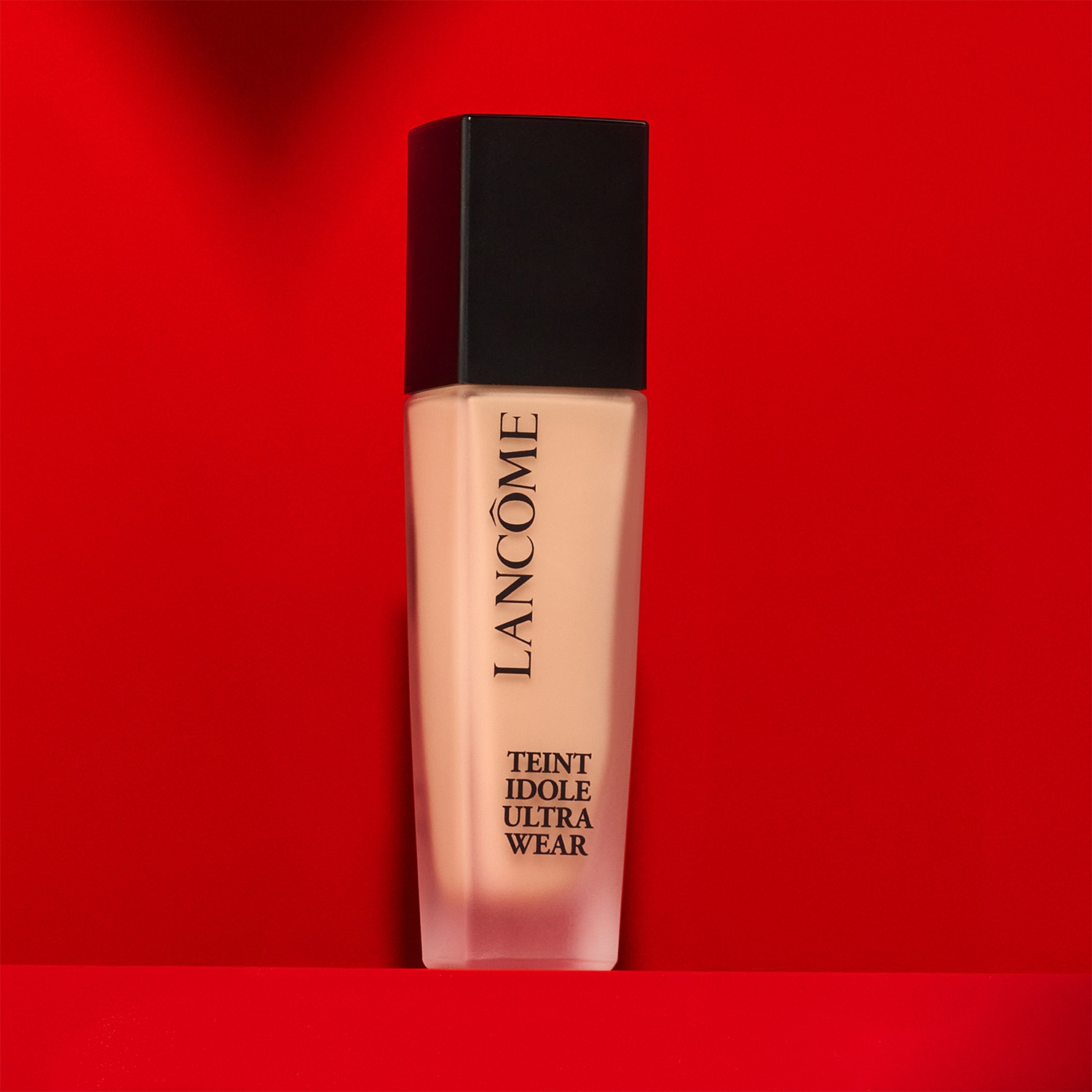 Découvrez le fond de teint Teint Idole Ultra Wear de Lancôme, présenté dans un élégant flacon en verre dépoli avec un bouchon noir, offrant une couvrance impeccable et un fini naturel.