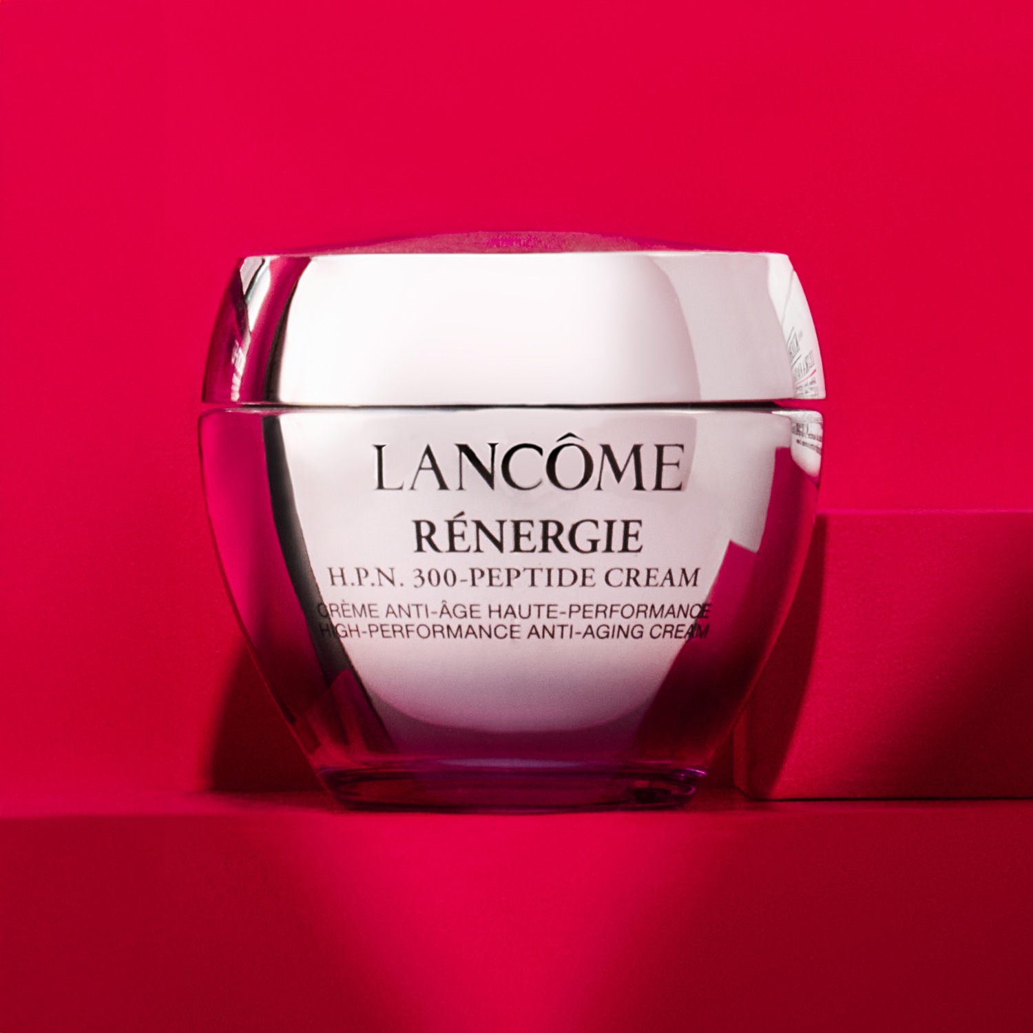 Découvrez la Crème Rénergie H.P.N. 300-Peptide de Lancôme, un soin anti-âge haute performance dans un élégant pot argenté, sur un fond rose vibrant.