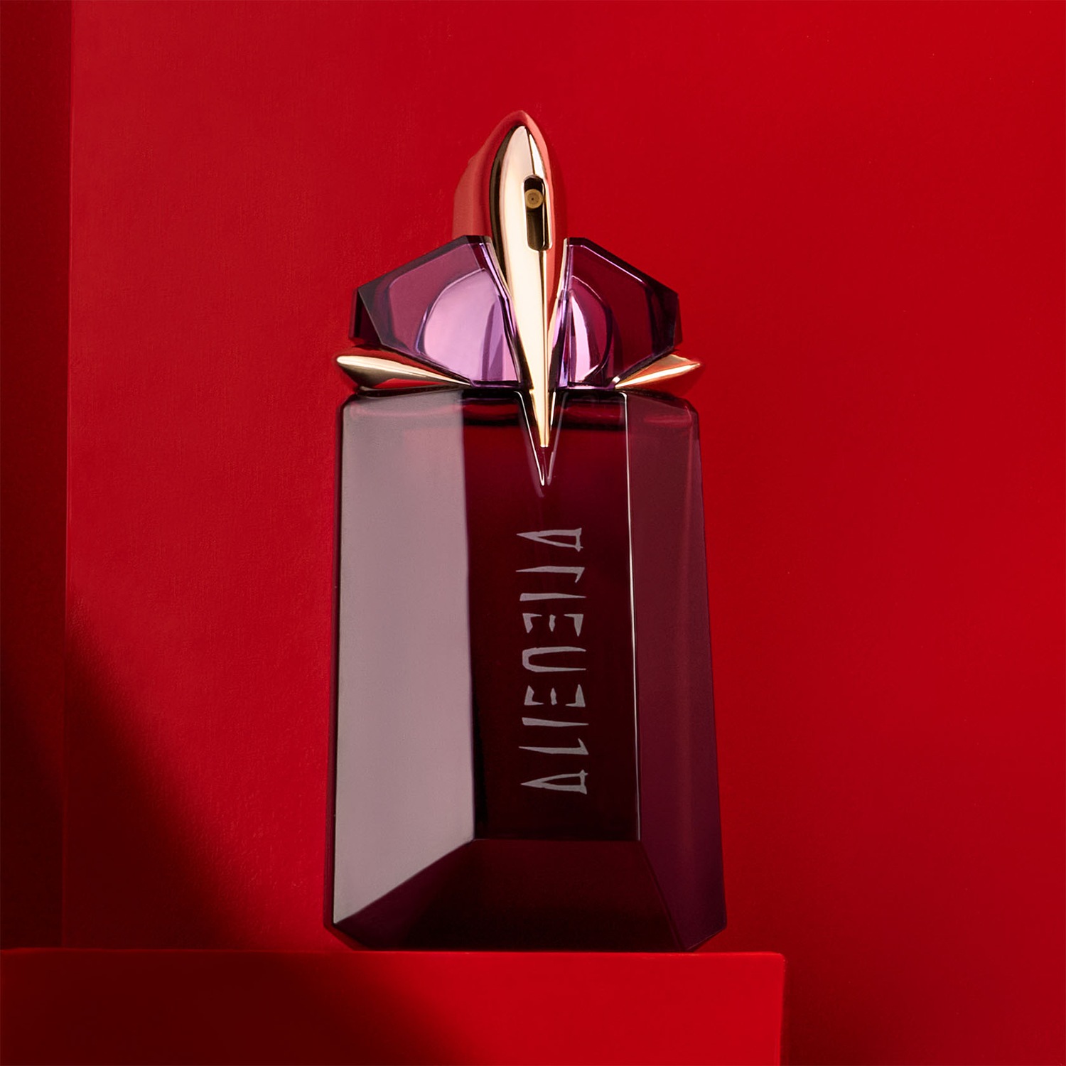 Découvrez Alien, un parfum envoûtant dans son flacon rouge profond, coiffé d'un bouchon doré étincelant, promesse d'une expérience olfactive inoubliable.