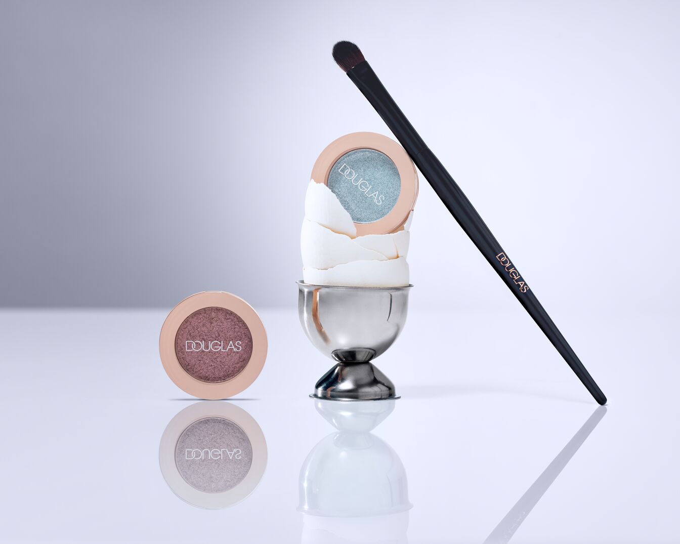 Ombretto Douglas color bronzo e azzurro pastello in confezione rotonda color pesca, pennello nero con logo Douglas.