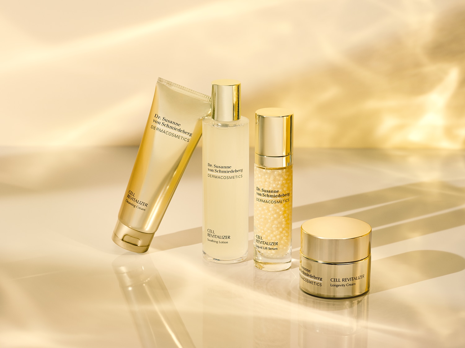 Découvrez la collection Dr. Susanne von Schmiedeberg DERMACOSMETICS, comprenant une crème nettoyante, une lotion apaisante, un sérum liftant liquide et une crème de longévité, le tout dans un emballage doré élégant.