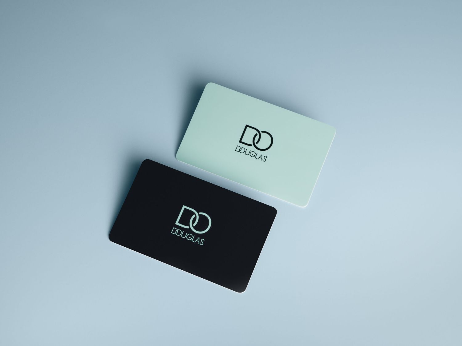 A képen két Douglas ajándékkártya látható: egy világos és egy sötét, mindkettőn a Douglas logója szerepel.