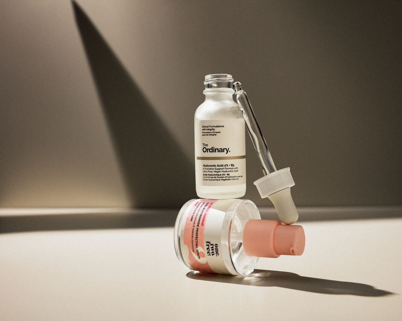 Das Foto zeigt eine weiße Flasche "The Ordinary" Hyaluronsäure 2% + B5 und eine durchsichtige Flasche "one.two.free!" 10% Niacinamid Perfektionsserum.