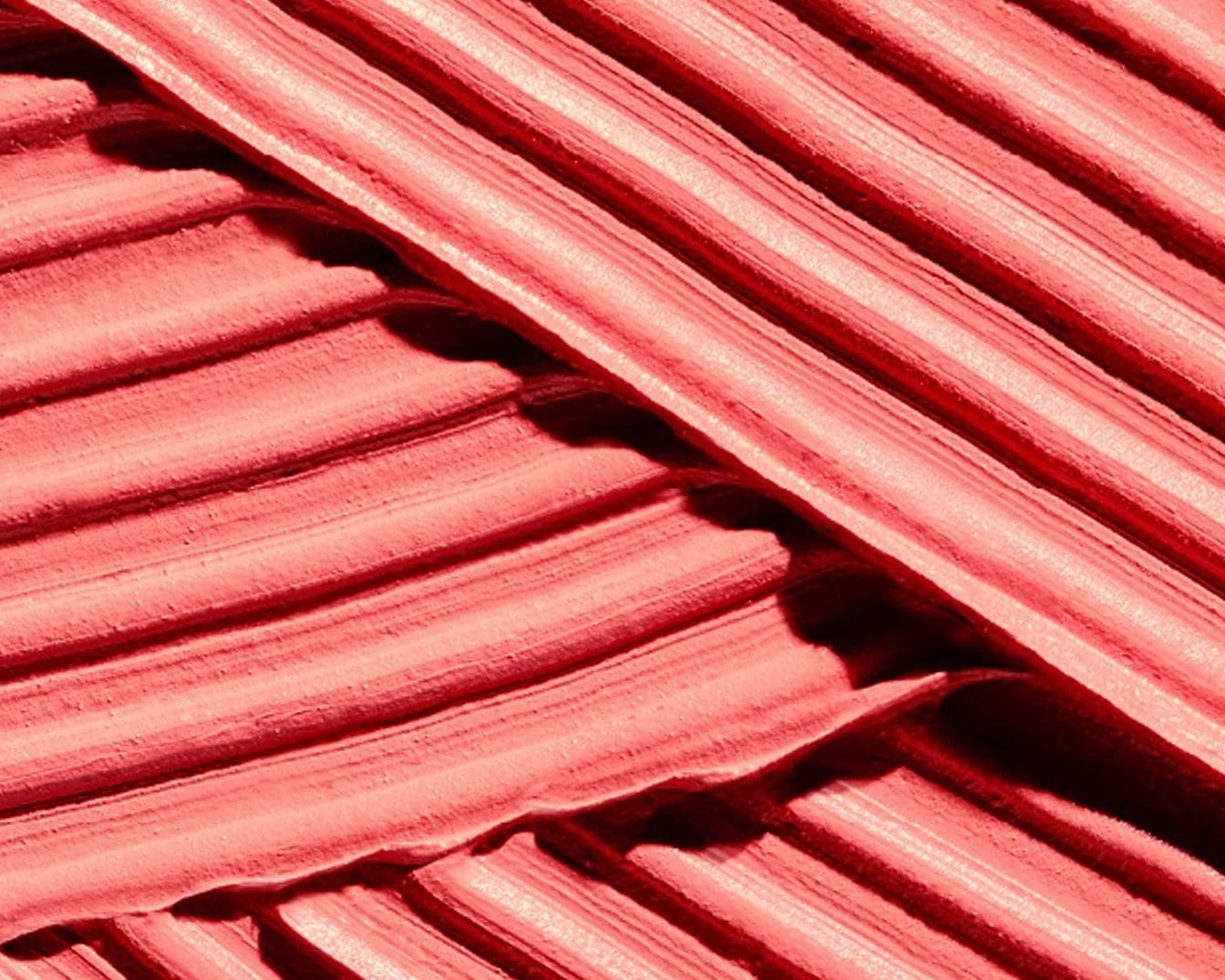 Šis vaizdas rodo raudonos spalvos kreminės tekstūros kosmetikos gaminio tepinėlį, kuris gali būti lūpų dažai ar skaistalai, sukurdamas sodrų ir aksominį efektą.